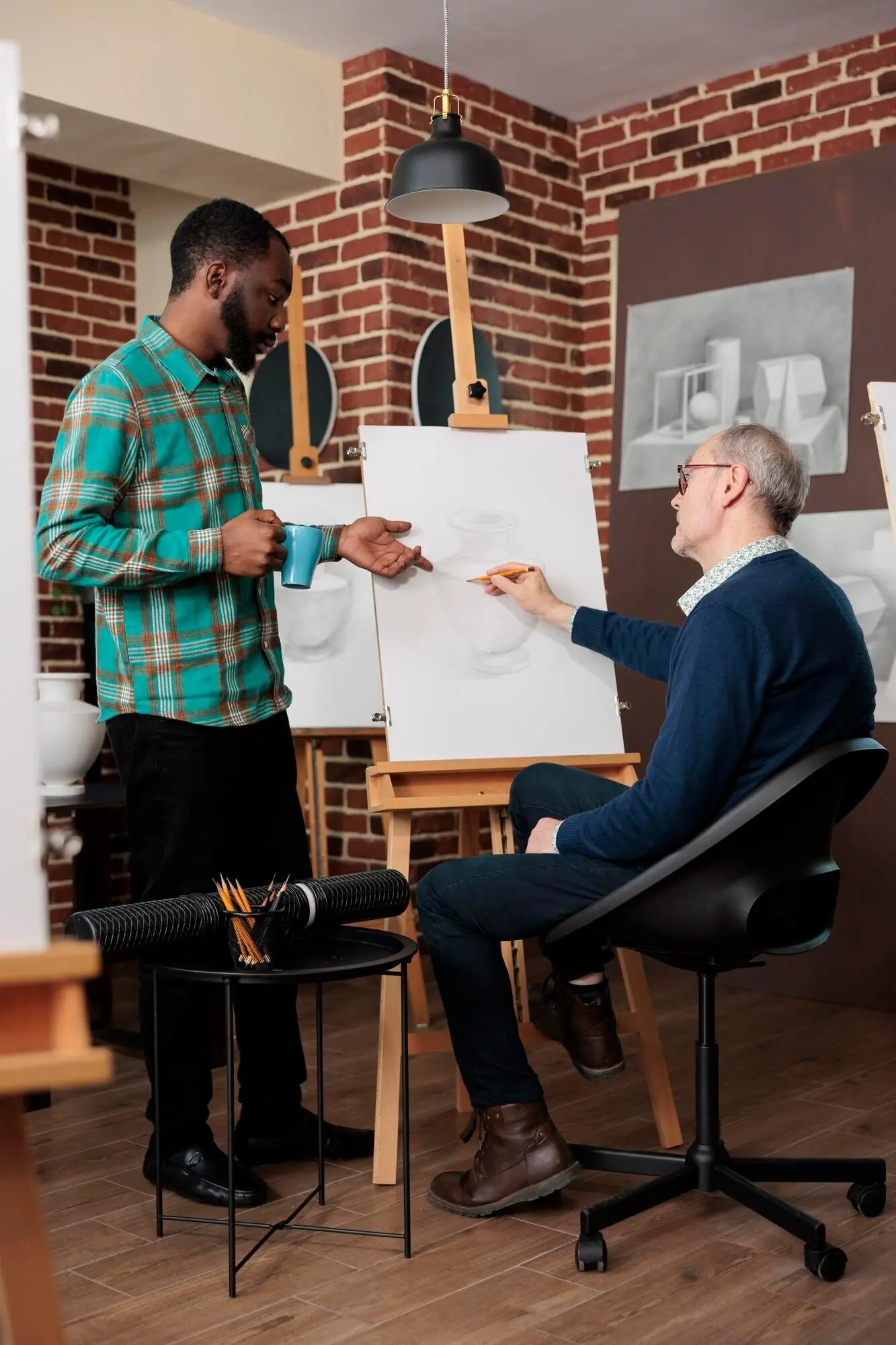 Hombre mayor que asiste a clases de arte e interactúa con otros estudiantes y profesores durante una lección de dibujo; personas que aprenden algo nuevo en la jubilación. Actividades creativas de trabajo en equipo.